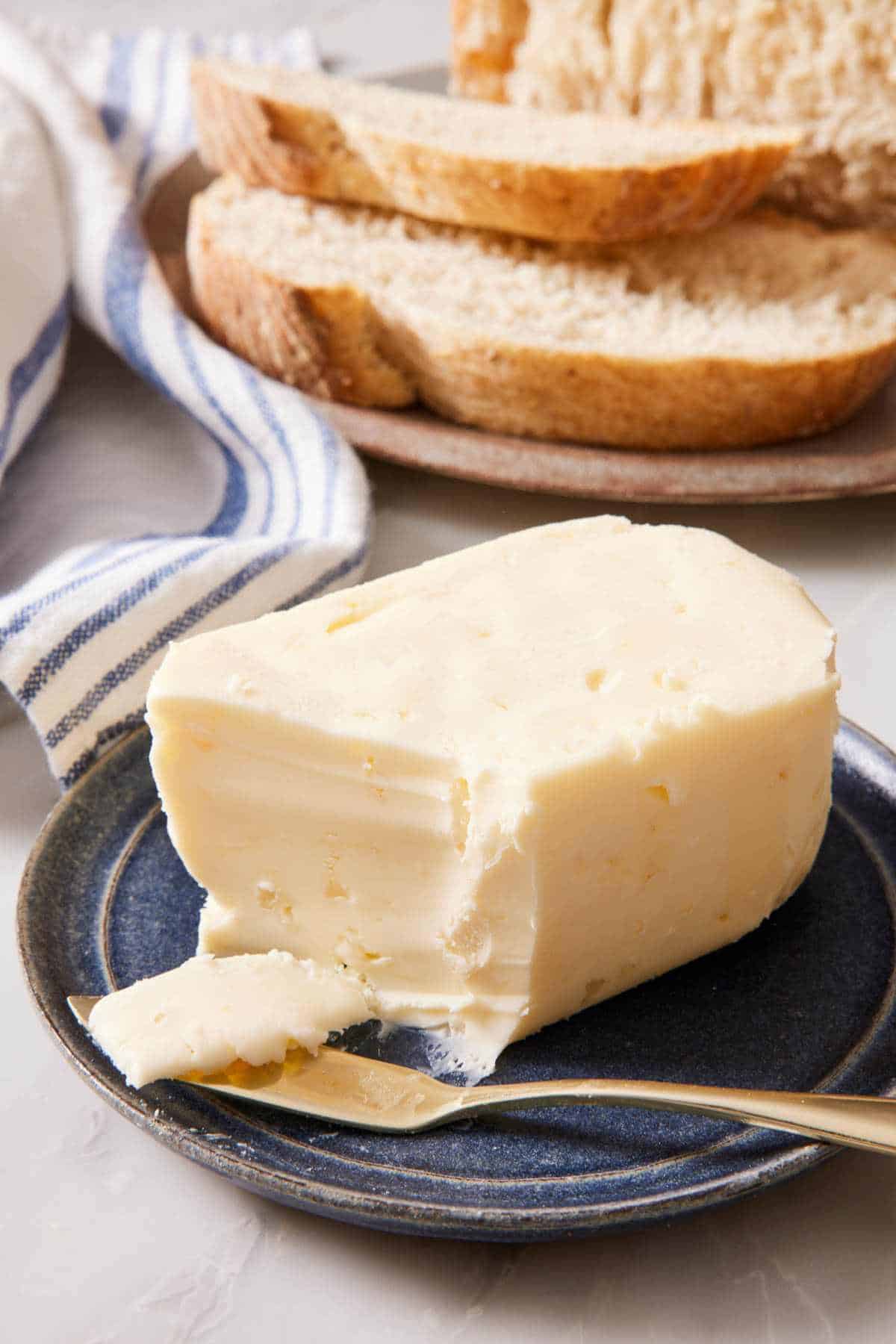 Close-up of a block of butter on a small plate with some shaved off onto a butter spreader.